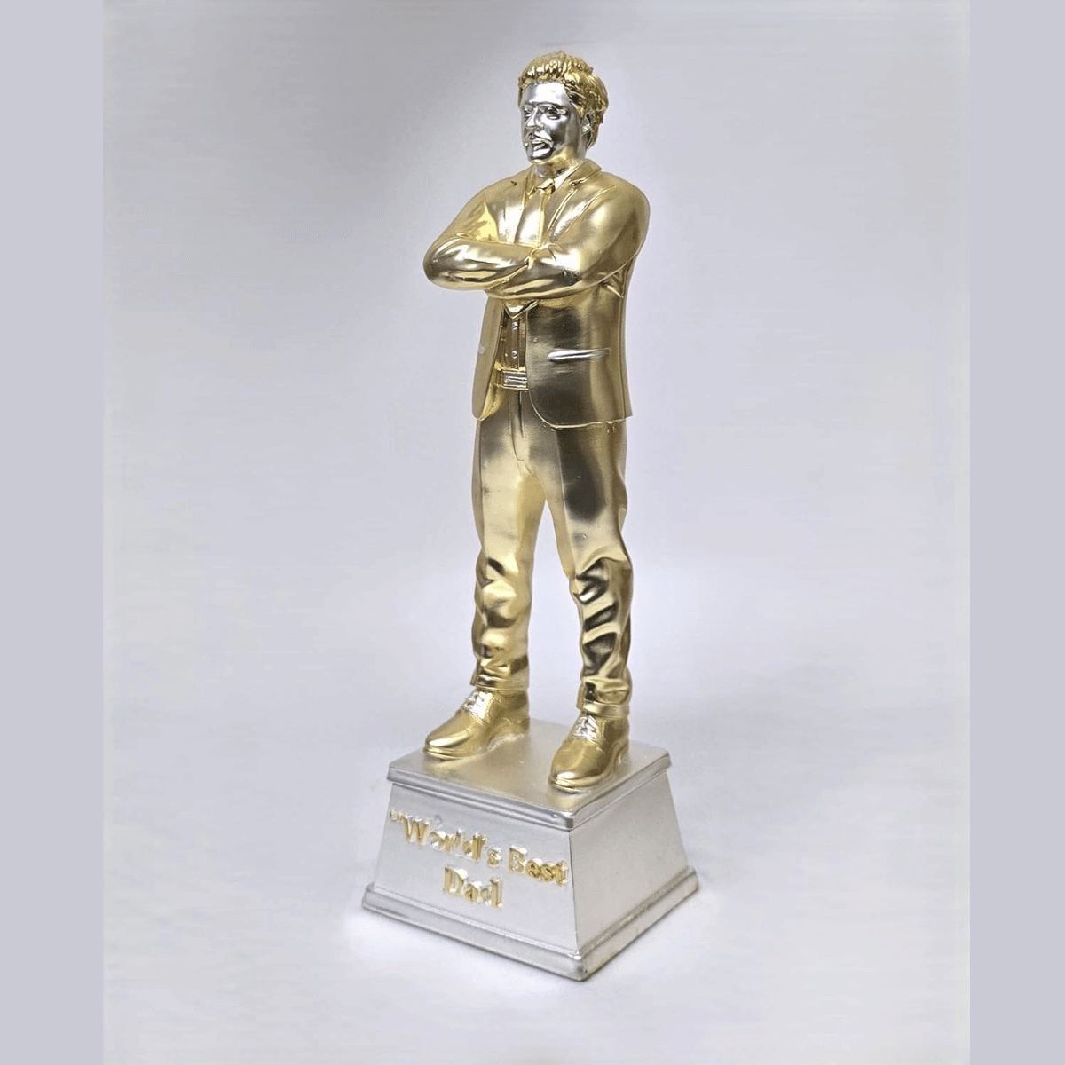 "Gold and silver-plated 'World's Best Dad' figurine, standing 9 inches tall with a 3-inch wide base, featuring a stylish man in a suit with crossed arms, ideal as a Father's Day or birthday gift."