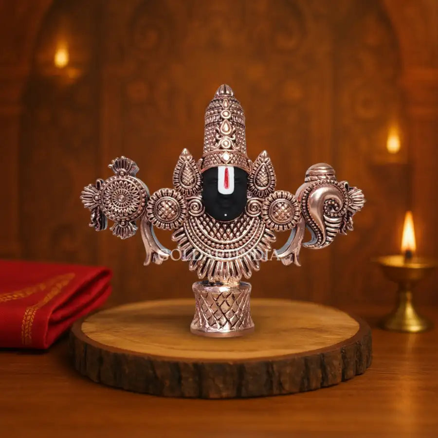 Antique copper-finish Lord Balaji idol with black face on wooden base.