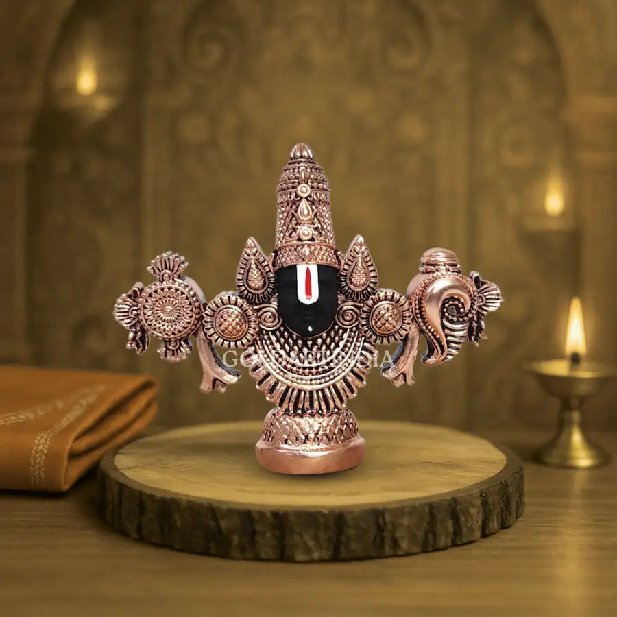 Antique copper-finish Lord Balaji idol with black face on wooden base.