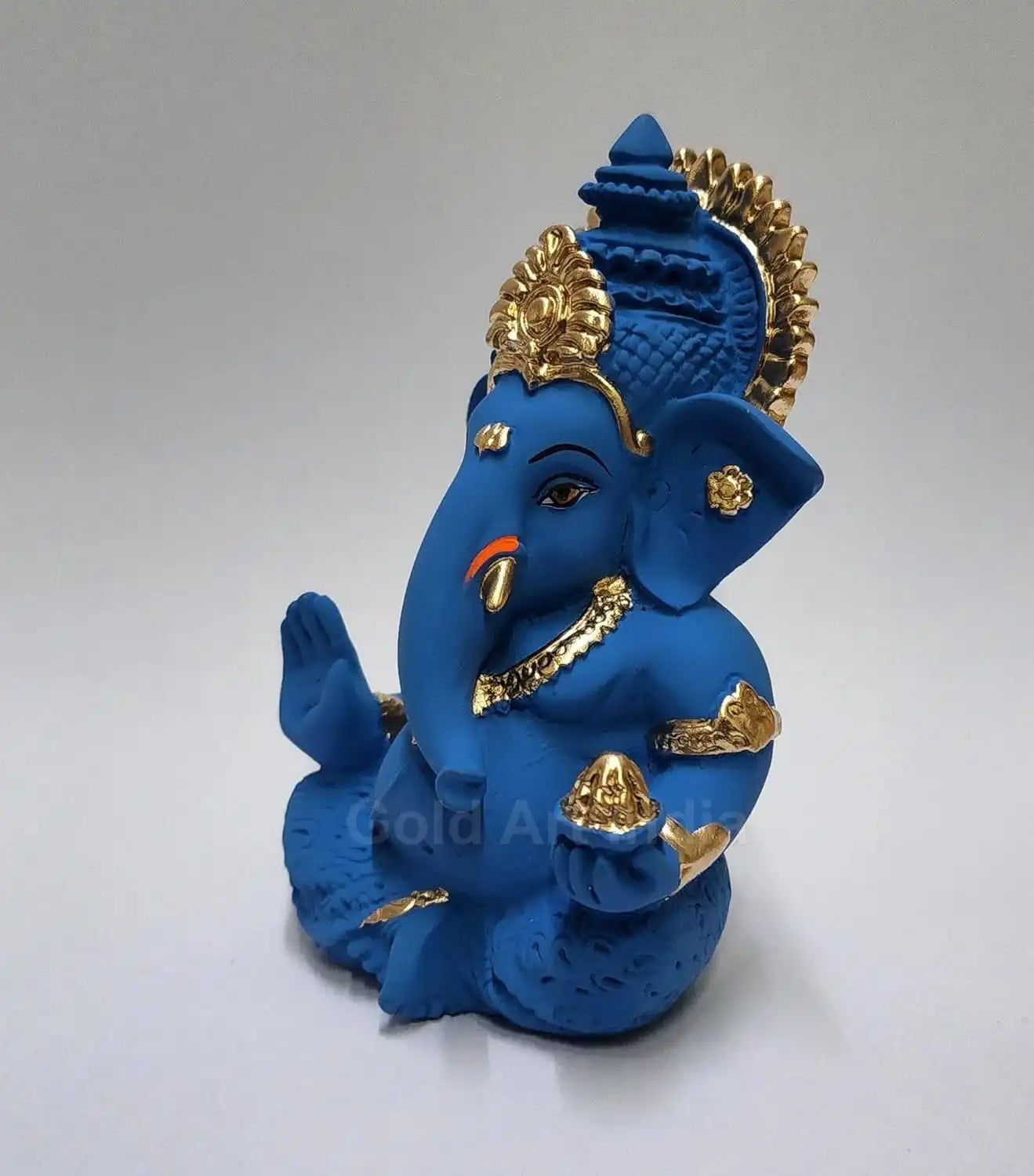 mango terracotta Ganesha idol with Gold detailing, seated in a blessing posture, holding a modak in one hand. back view