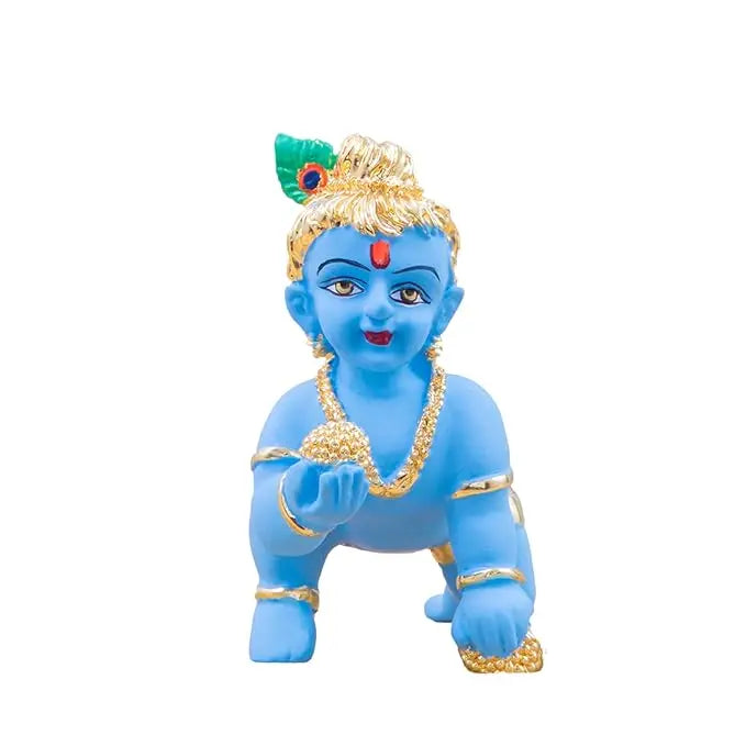blue-colored Baby Krishna idol in a crawling pose, adorned with gold jewelry, a peacock feather on his head, and holding a golden laddu in his hand