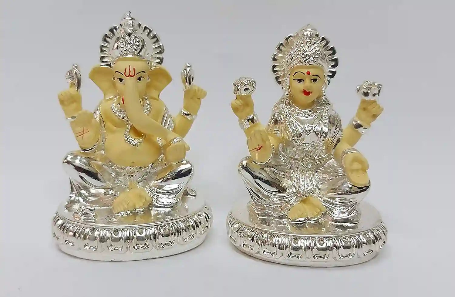 Front view of Lakshmi and Ganesha resin idol set, silver plated with delicate off-white detailing, seated on decorative base