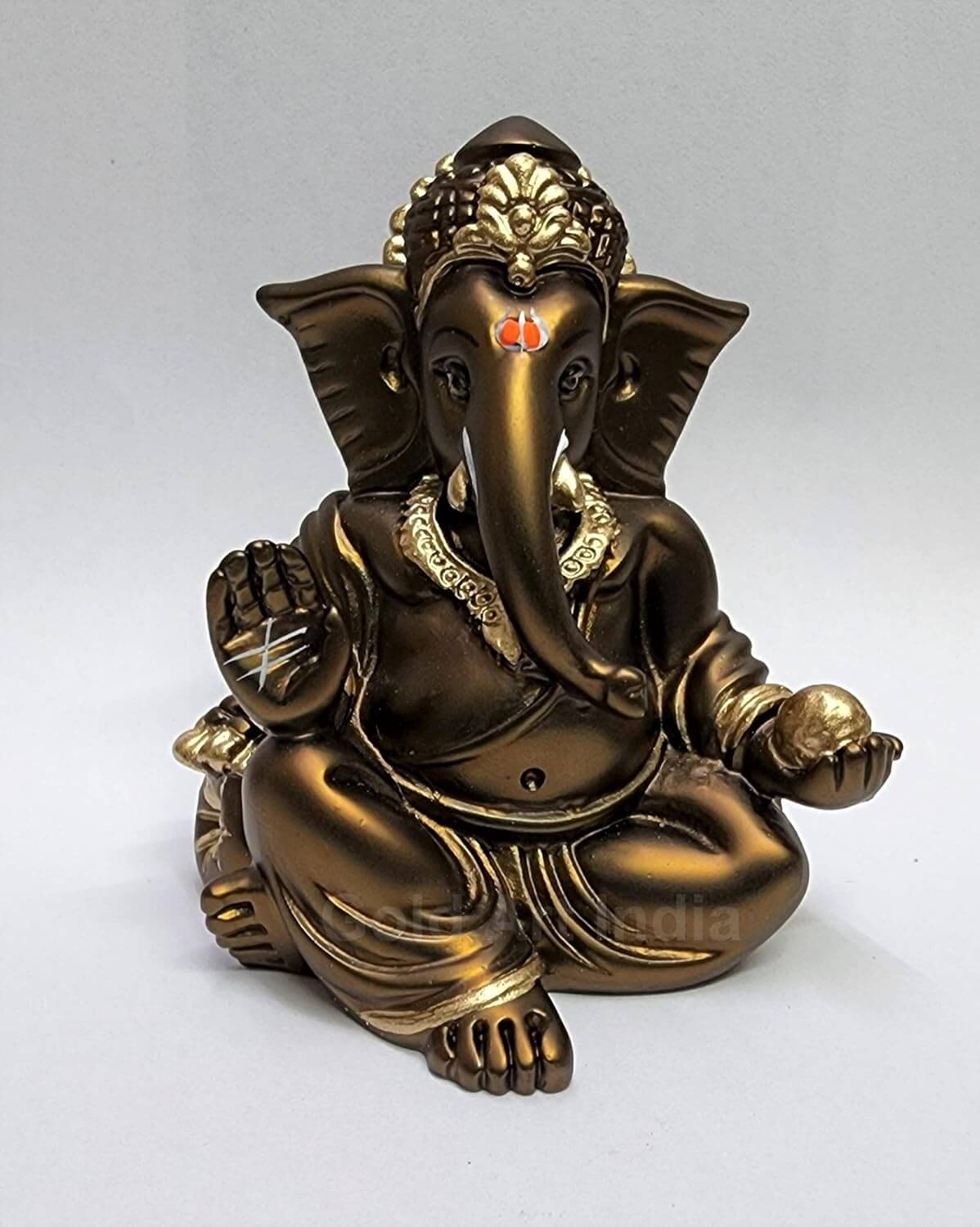 A 3.5-inch bronze-colored Ganesha statue with a crown, jewelry, and intricate carvings. One hand gives blessings, the other holds a golden ladoo.