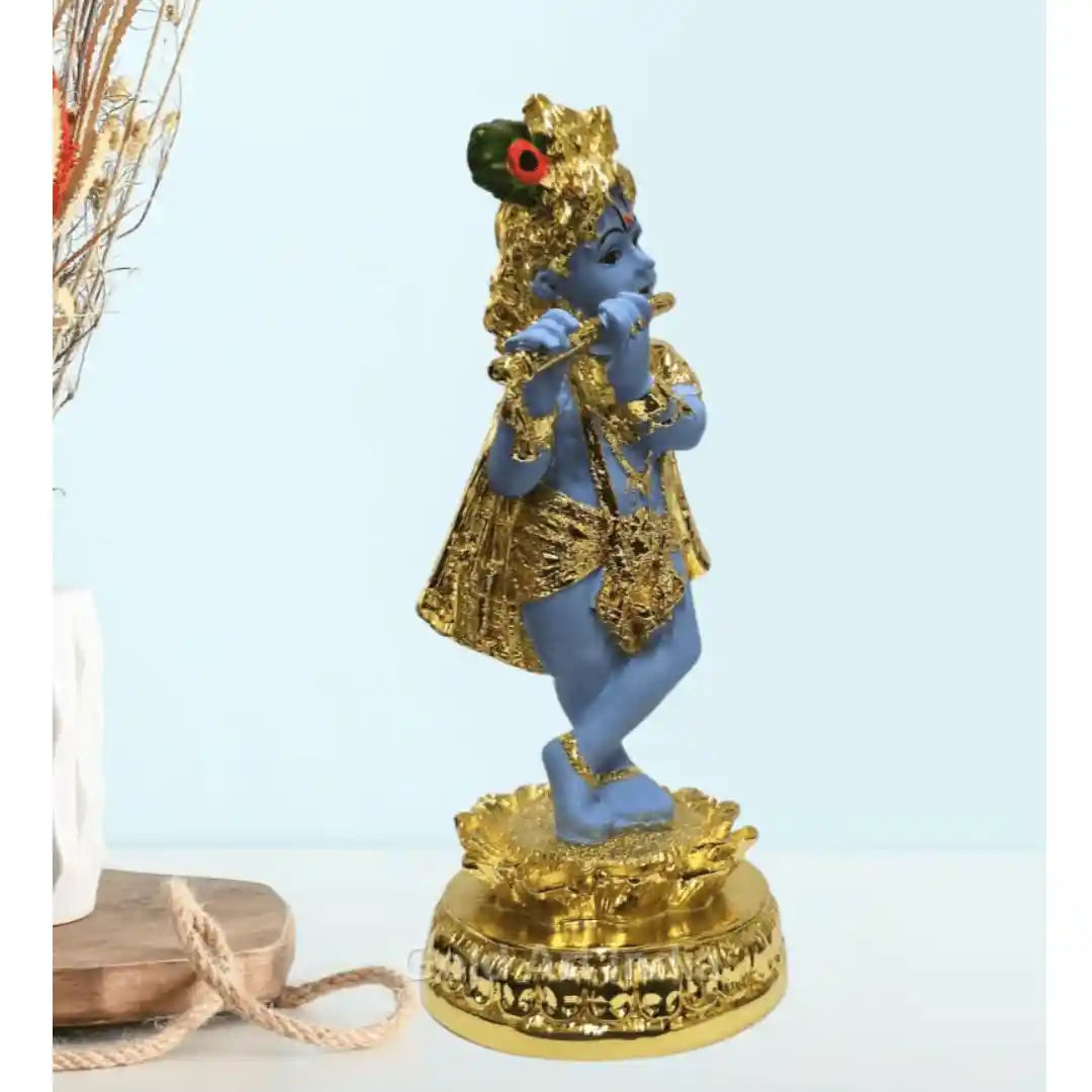 Gold-plated Krishna idol playing the flute, beautifully designed with a blue body and golden ornaments, standing on a decorative base
