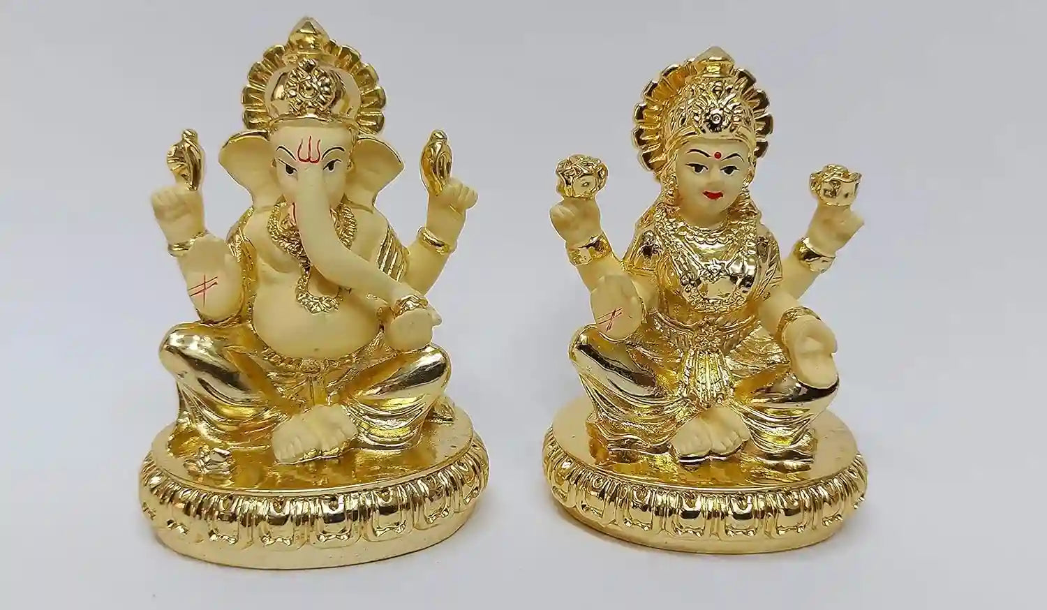 Angled side view of Lakshmi and Ganesha idols with gold plating and off-white enamel work, highlighting premium finish.