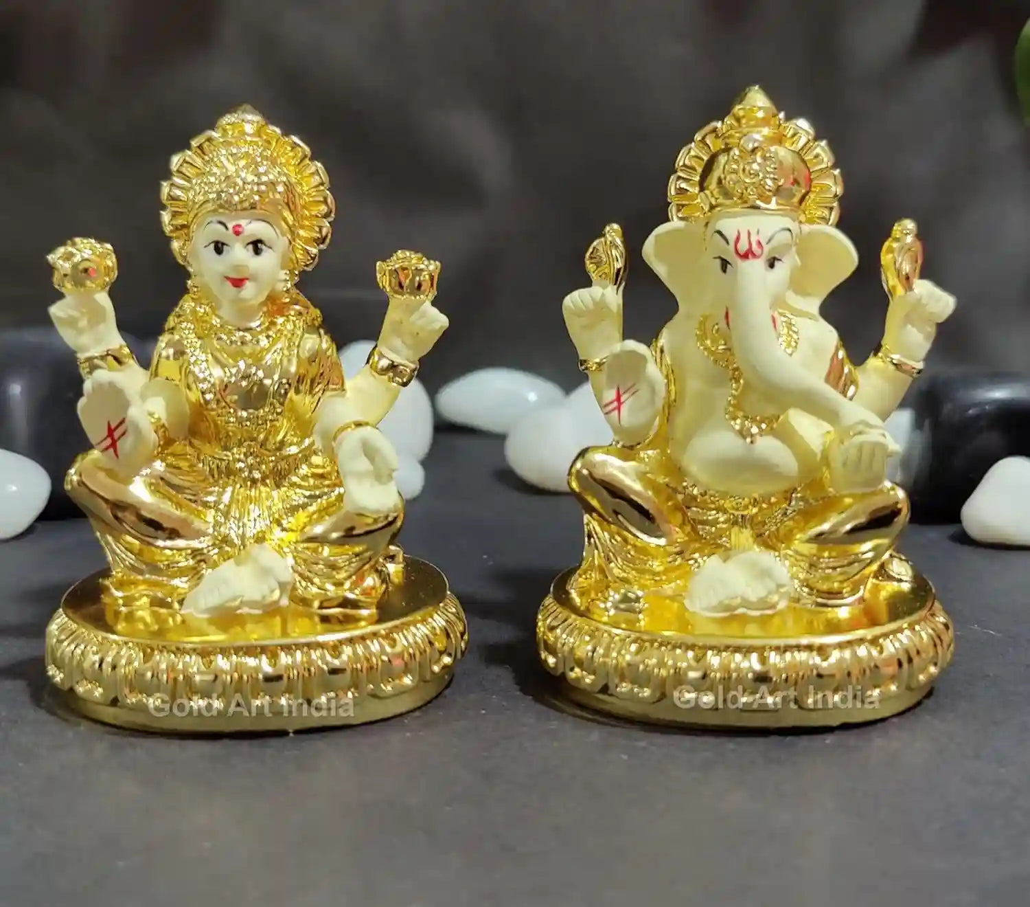 Gold plated Lakshmi and Ganesha resin idols with off-white detailing, seated on lotus pedestal with intricate craftsmanship.