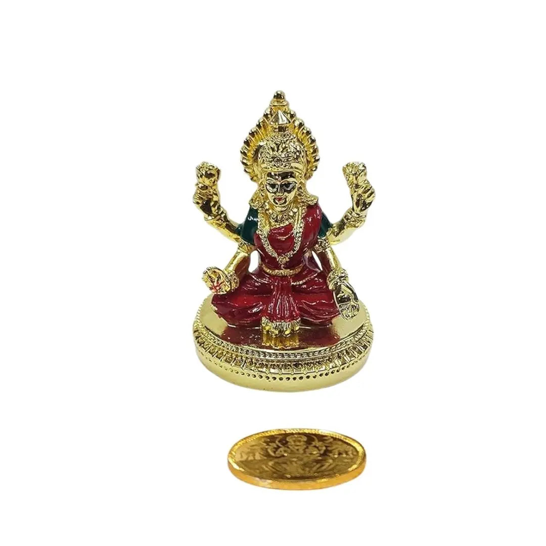 Gold plated Lakshmi idol with vibrant red enamel finish, seated on round base, paired with gold-plated coin symbolizing prosperity.