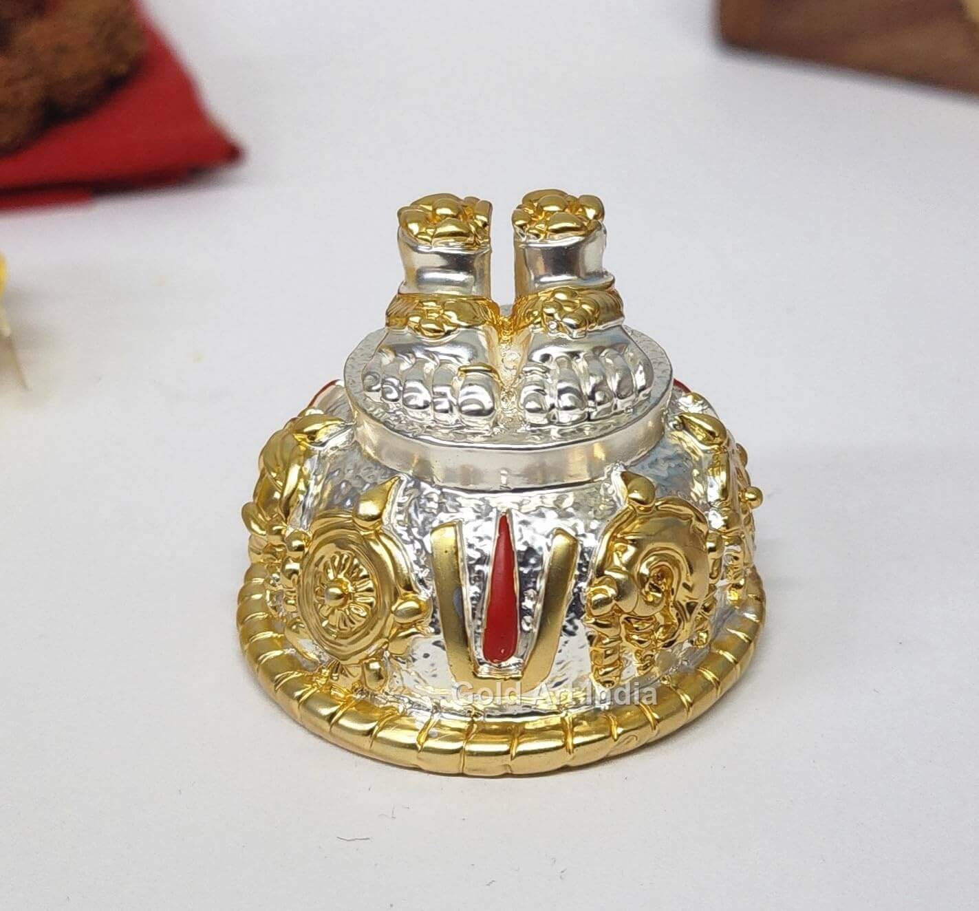 A silver and gold decorative idol featuring Lord Balaji's feet (Paduka) with intricate carvings of religious symbols and ornaments.