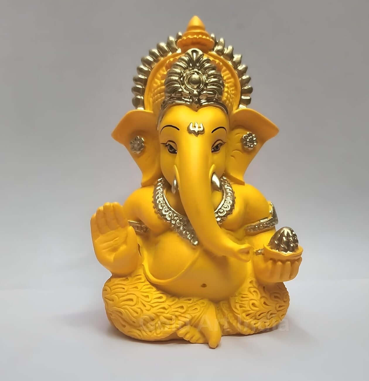 mango terracotta Ganesha idol with Gold detailing, seated in a blessing posture, holding a modak in one hand.
