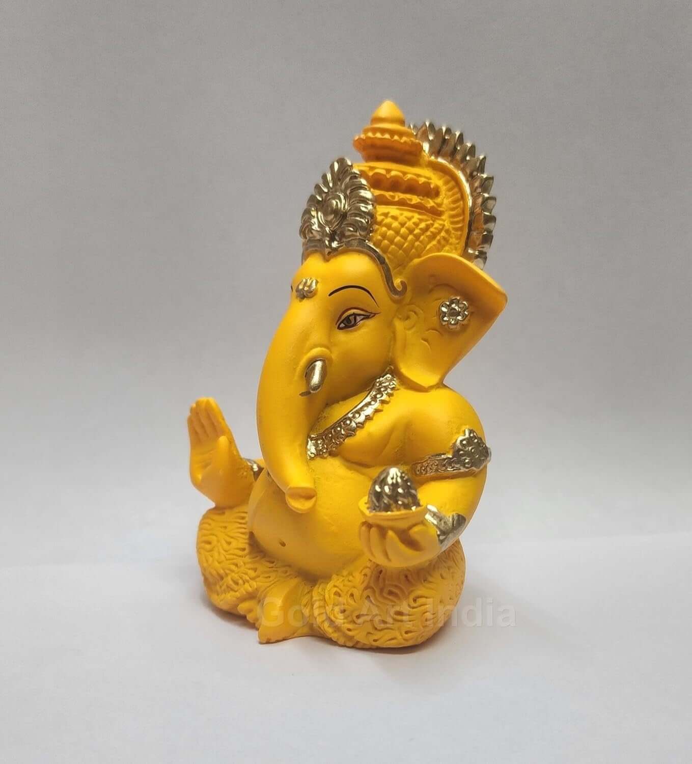 mango terracotta Ganesha idol with Gold detailing, seated in a blessing posture, holding a modak in one hand.