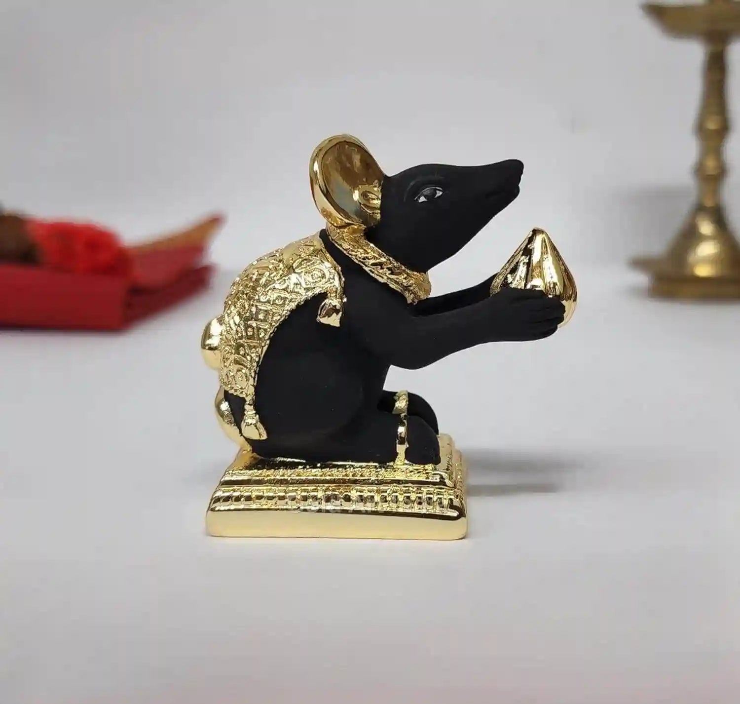 Side profile of handcrafted Mushak mouse idol with golden modak and black matte body
