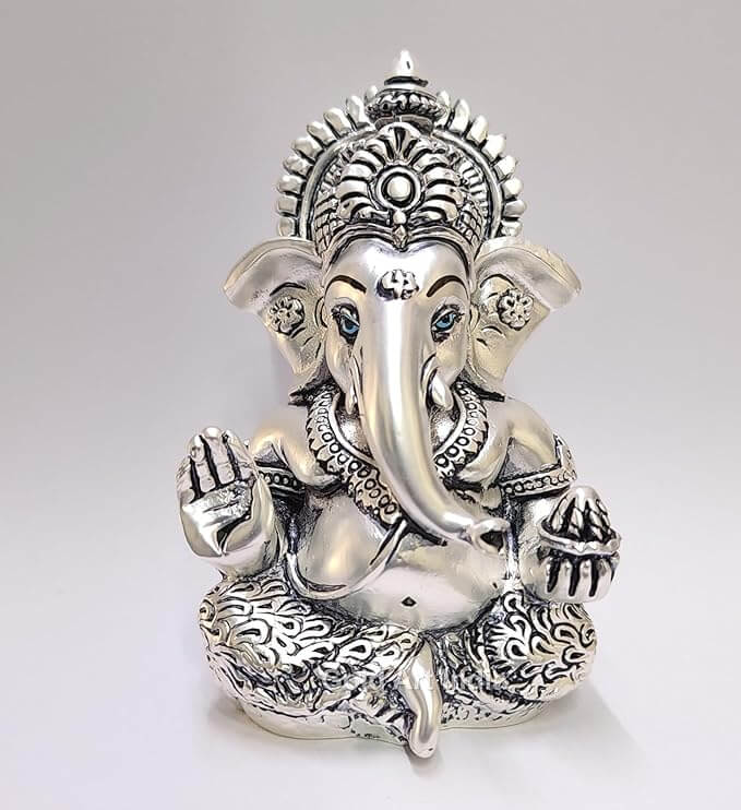 Silver Antique matte Ganesha idol with detailing, seated in a blessing posture, holding a modak in one hand.