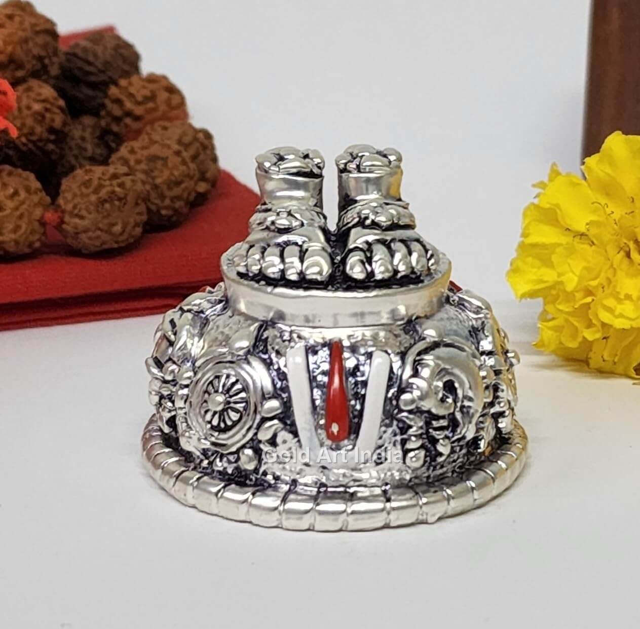 A silver Plated decorative idol featuring Lord Balaji's feet (Paduka) with intricate carvings of religious symbols and ornaments.