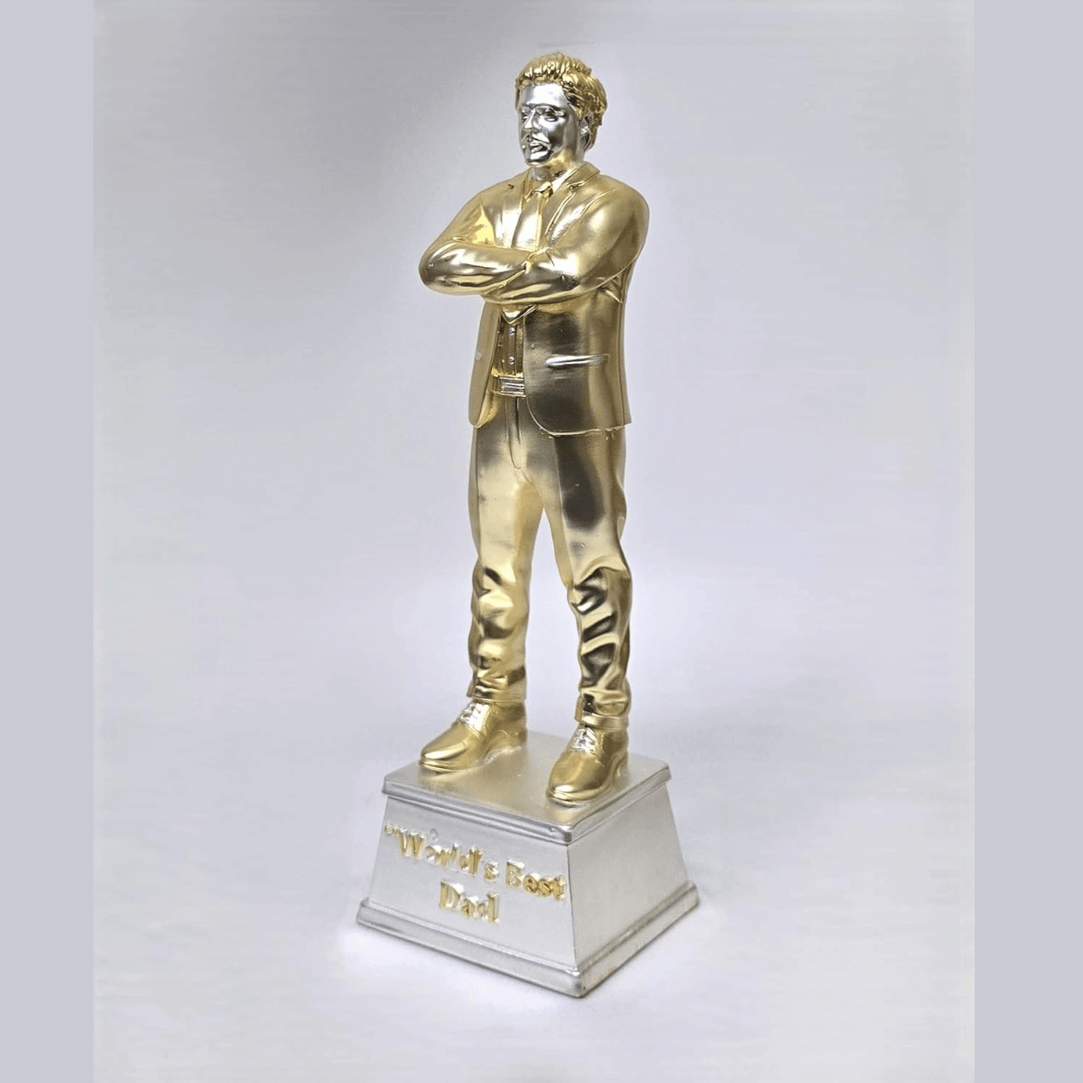 "Gold and silver-plated 'World's Best Dad' figurine, standing 9 inches tall with a 3-inch wide base, featuring a stylish man in a suit with crossed arms, ideal as a Father's Day or birthday gift."