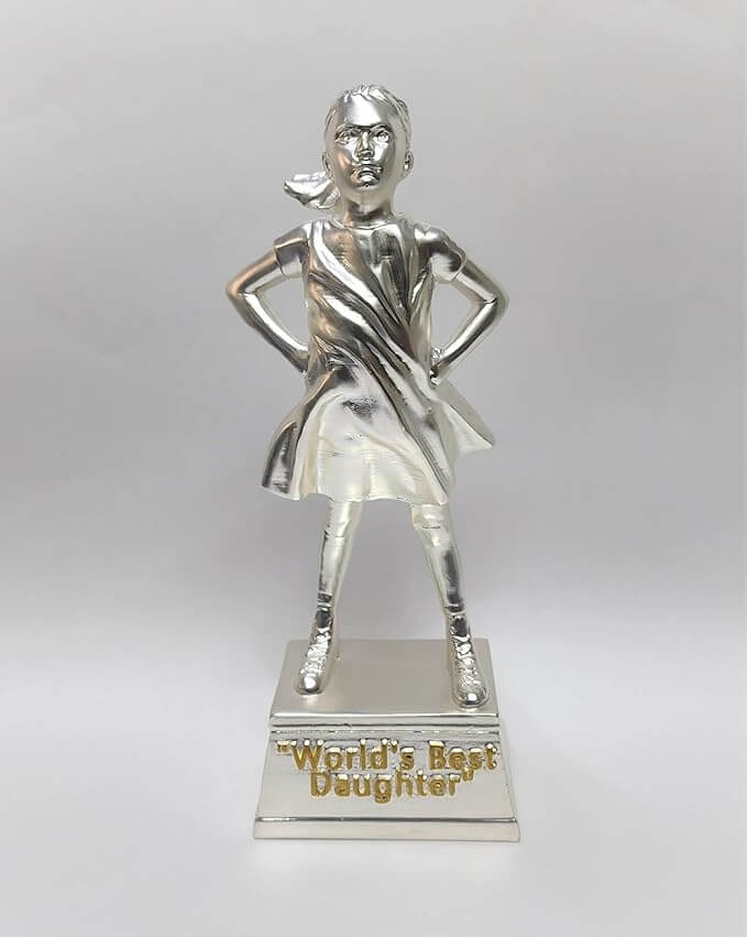 A silver-plated trophy of a confident young girl standing with her hands on her hips. The figure is fully silver, with a flowing dress and ponytail. The trophy stands on a rectangular silver base with the engraved text "World's Best Daughter" .