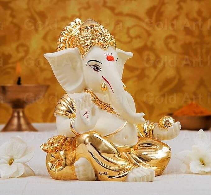 Side view of off-white and gold-plated Ganesha idol