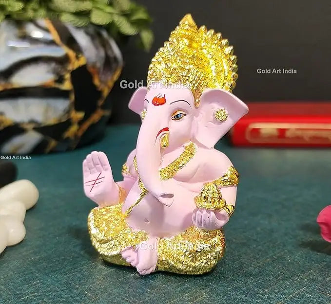 Side view of a white and gold Lord Ganesha idol with intricate detailing, a blessing hand, and a modak in the other.
