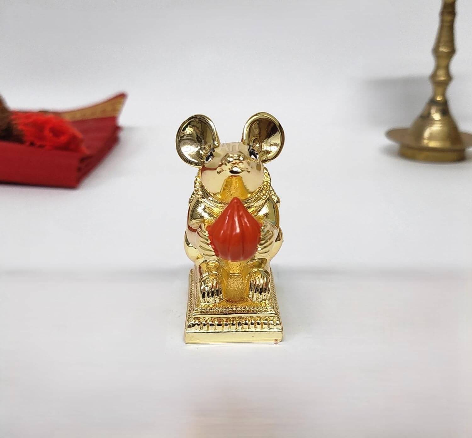 Gold-plated Mushak rat idol with intricate carvings, sitting on a decorative base, holding a Modak offering in its paws