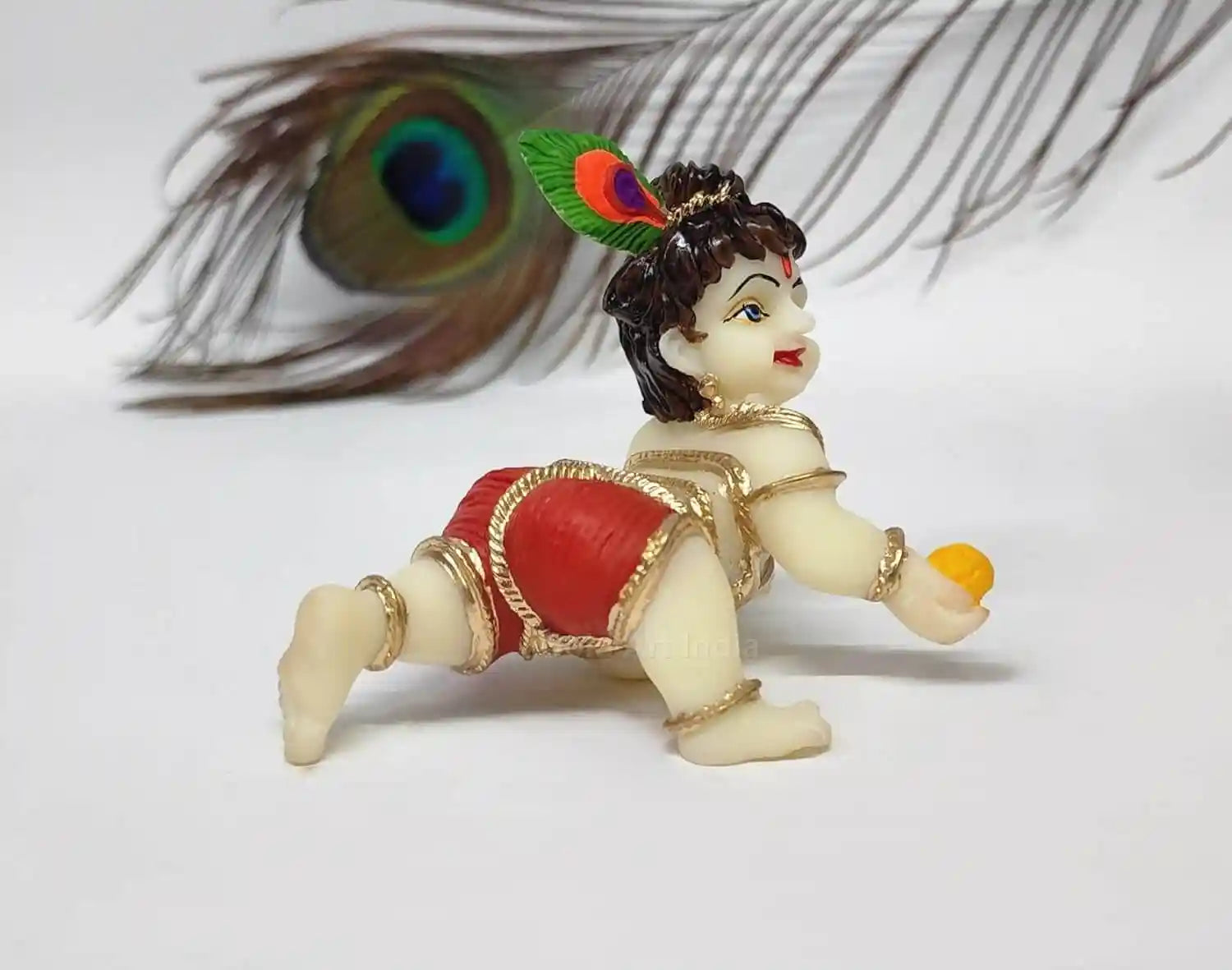 Ivory Laddu Gopal idol in red dhoti, depicting Lord Krishna with playful pose, ideal for Pooja and home decor.