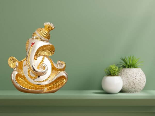 A 7-inch gold and silver plated abstract Ganesha idol placed on a shelf with a green background and decorative items beside it.