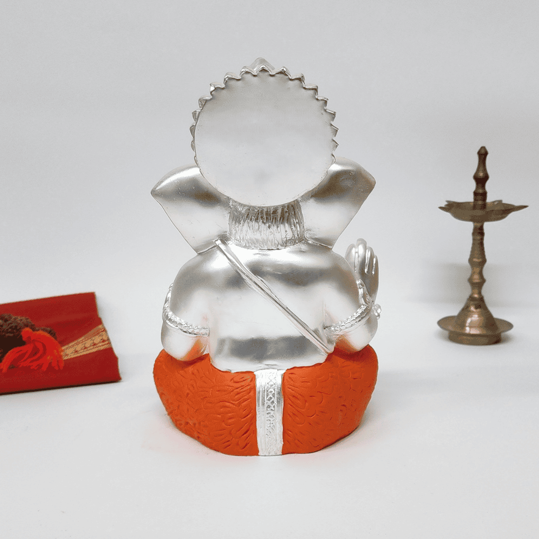 Back view of Silver Matte Mukut Ganesh Idol in orange dhoti, showcasing detailed craftsmanship and spiritual significance.