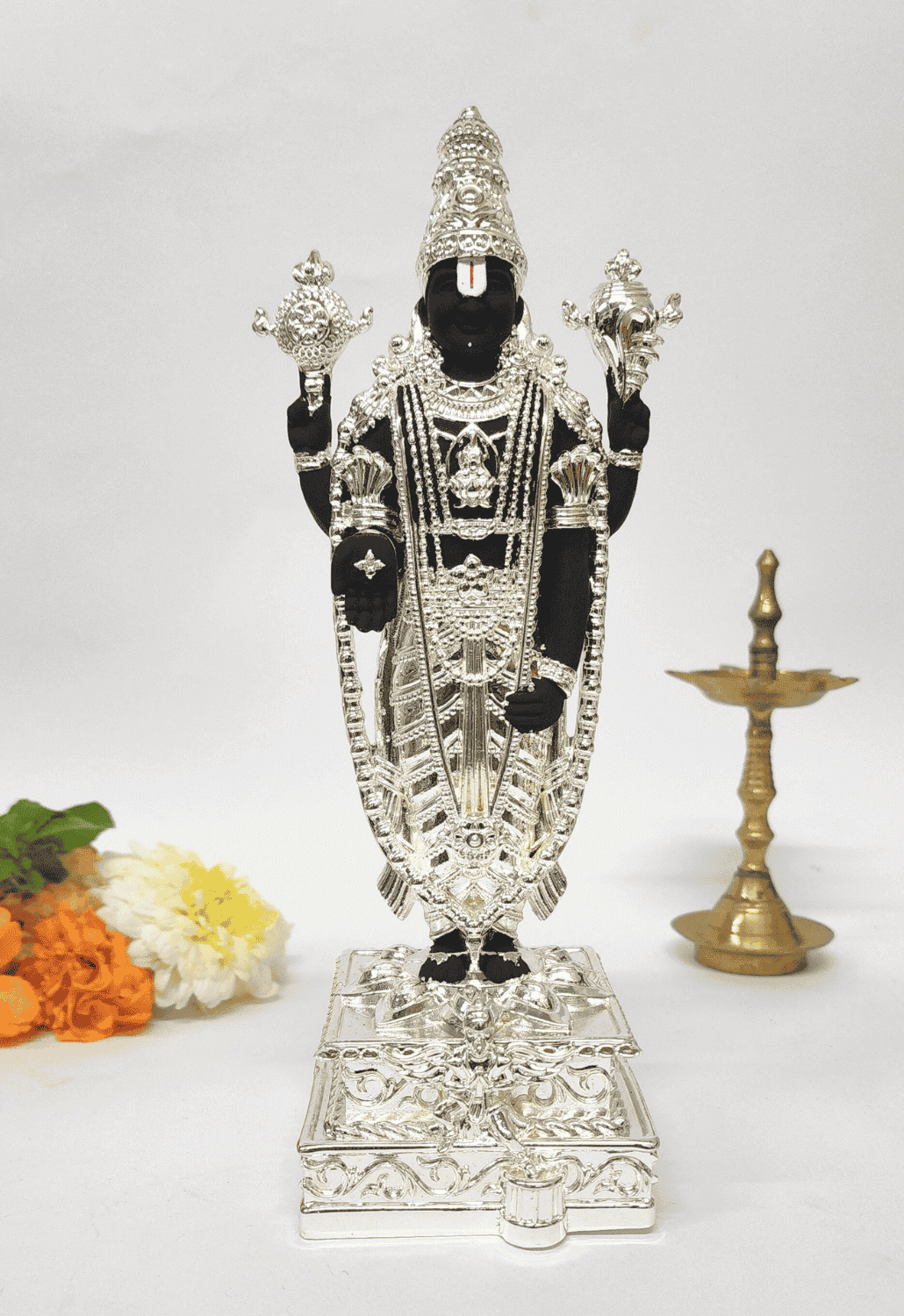Black and silver Lord Venkateshwara idol, elegantly adorned with intricate silver detailing, standing on an ornate pedestal.