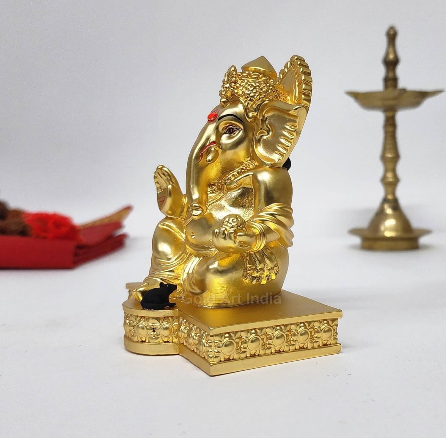 Elegant gold-plated Lord Ganesha idol with intricate detailing, seated on a decorative pedestal, symbolizing wisdom, prosperity, and good fortune. Perfect for home decor, puja rituals, or as a spiritual gift.
