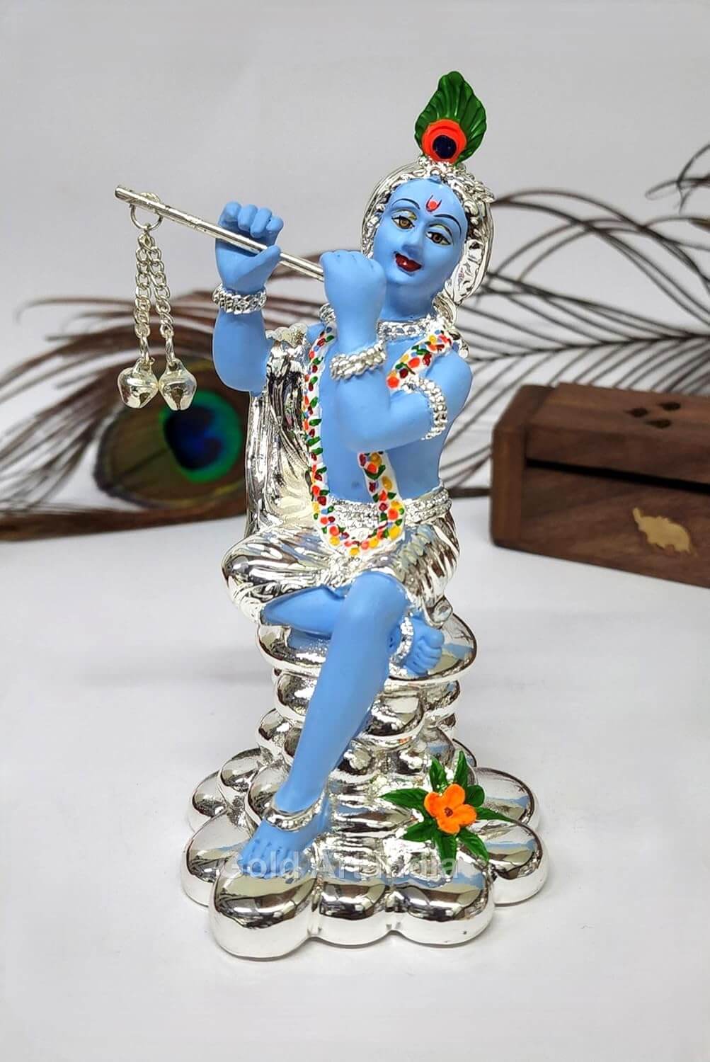 "A silver-Plated statue of Lord Krishna playing the flute, adorned with a peacock feather and colorful jewelry."