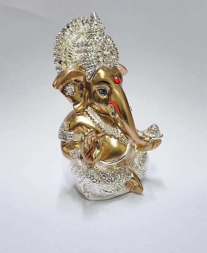 Silver Plated Antique Gold finish Ganesha idol with detailing, seated in a blessing posture, holding a modak in one hand.