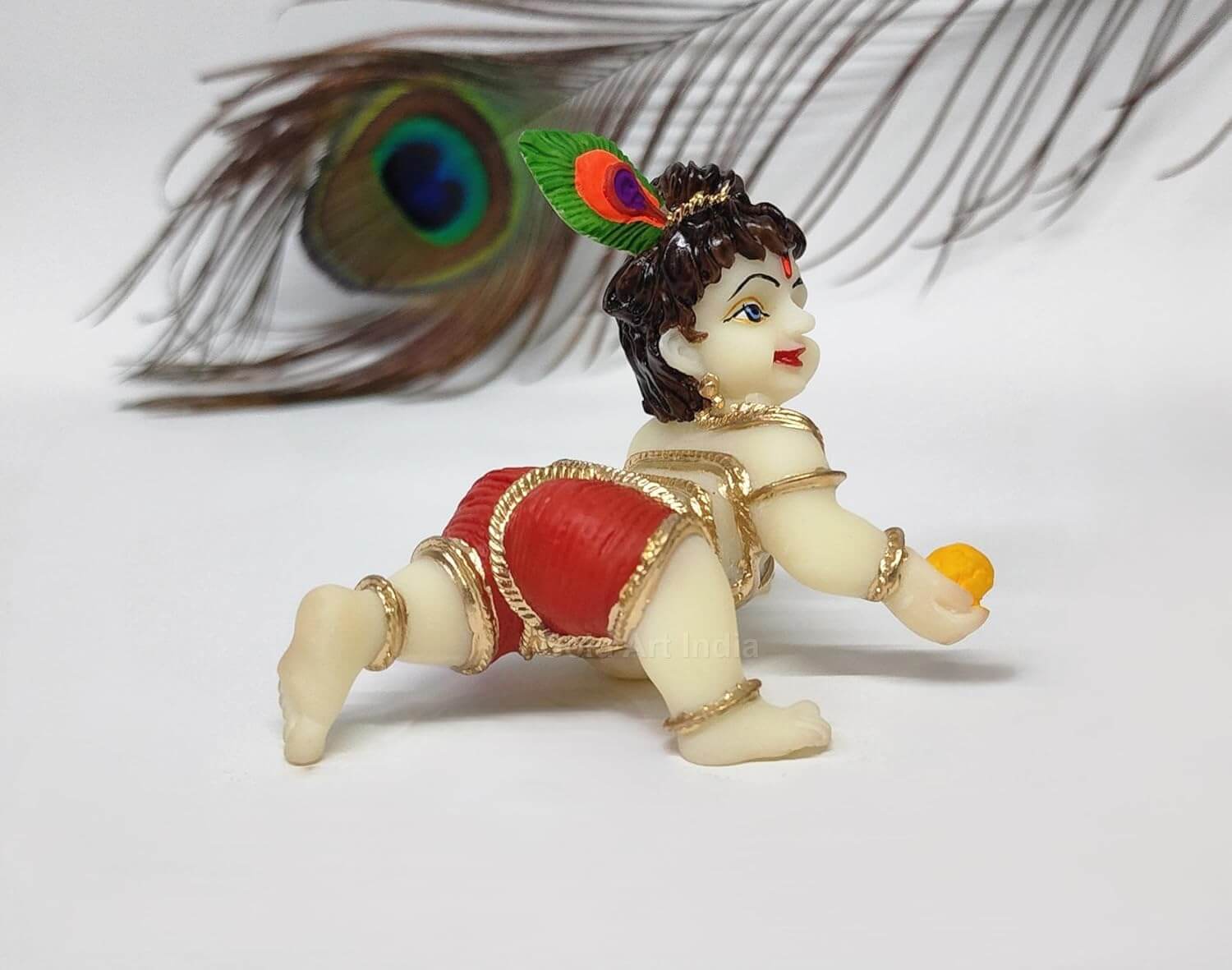 Ivory Laddu Gopal idol in red dhoti, depicting Lord Krishna with playful pose, ideal for Pooja and home decor.