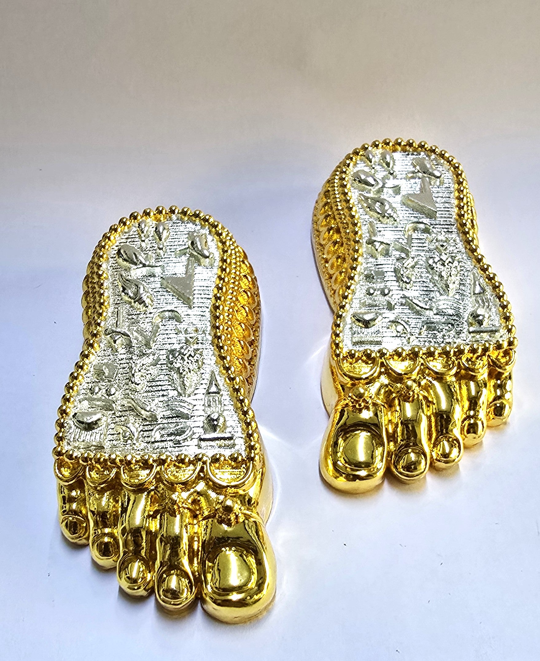 Pair of Laxmi Charan Paduka in gold and silver plating with detailed engravings, viewed from the front low angle