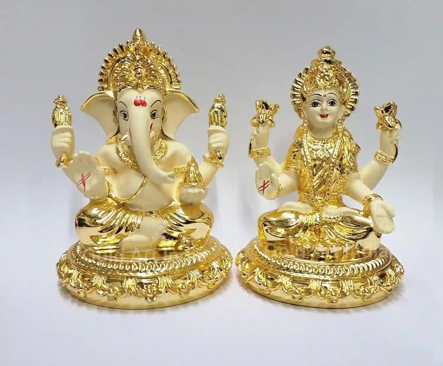 Gold plated off-white terracotta idols of Lord Ganesha and Goddess Laxmi sitting on intricately designed bases, ideal for puja, home decor, and gifting.
